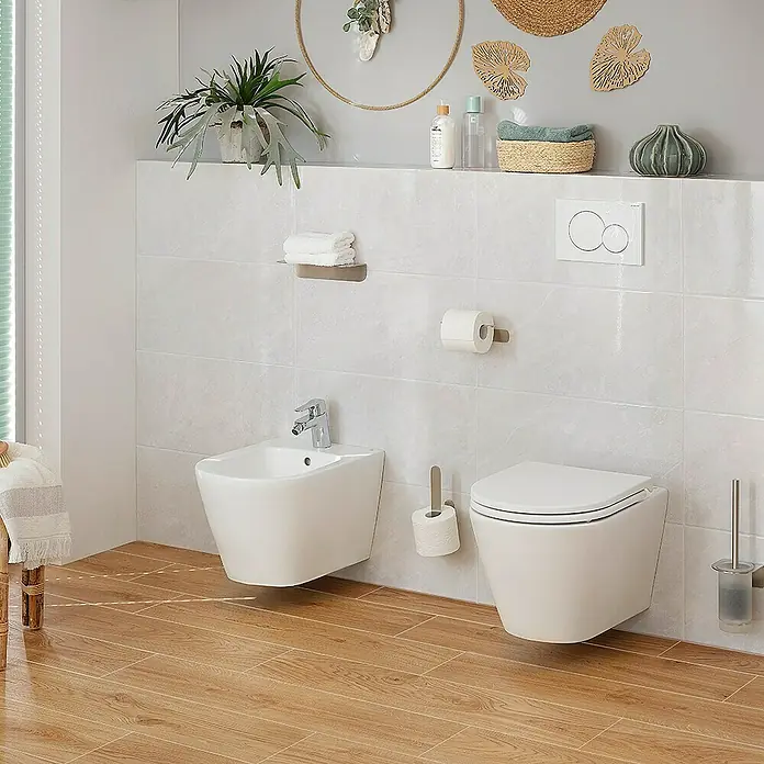 RAK Ceramics Feeling Wand-Bidet - 36 x 52 cm, Weiß, Keramik, Ohne Spezialglasur - Das Bild zeigt eine moderne Toilette und ein Bidet in einem Badezimmer mit hellen Fliesen und Holzboden. Die sanitären Anlagen sind stilvoll und sauber.