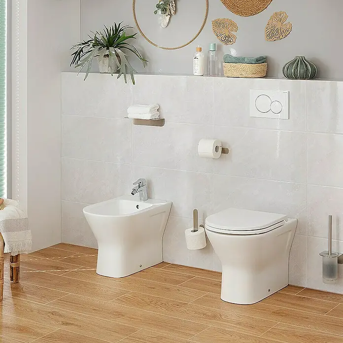RAK Ceramics Feeling Stand-WC - Spülrandlos, Ohne Spezialglasur, Spülform: Tief, WC Abgang: Waagerecht, Weiß - Das Bild zeigt ein modernes Badezimmer mit einer eleganten Toilette und einem Bidet in Weiß. Die sanfte Farbgebung schafft eine entspannende Atmosphäre.