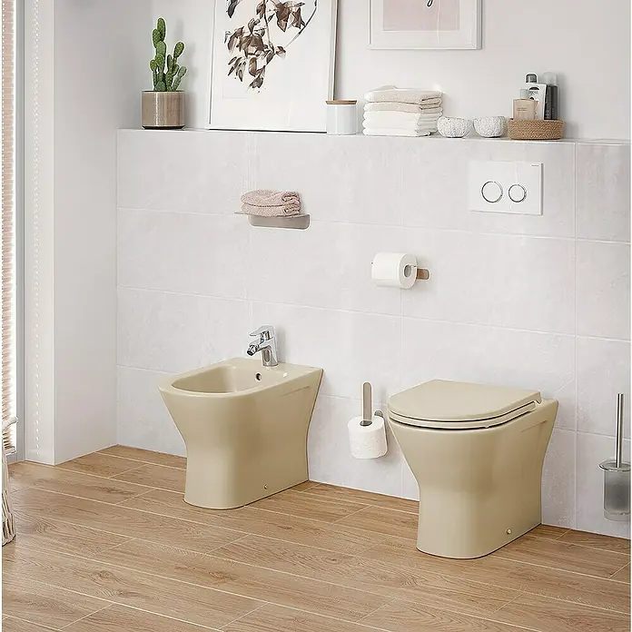 RAK Ceramics Feeling Stand-WCSpülrandlos, Ohne Spezialglasur, Spülform: Tief, WC Abgang: Waagerecht, Greige - Beige Toilette und Bidet mit Armatur in einem Badezimmer mit hellen Fliesen und Holzboden. Moderne Badausstattung für ein stilvolles Ambiente.