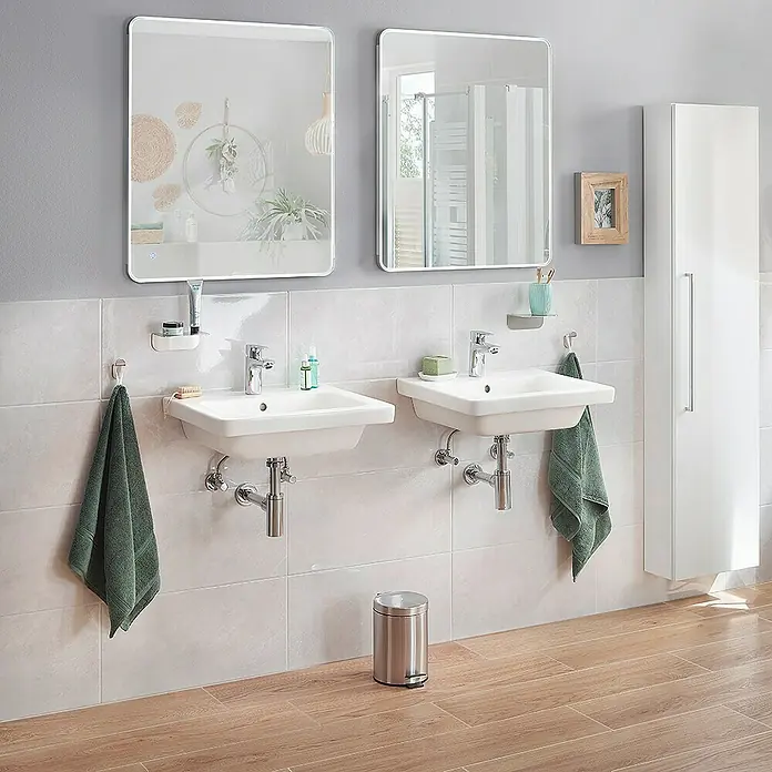 RAK Ceramics Feeling Waschtisch - 55 x 46 cm, Ohne Spezialglasur, Hahnloch: Mitte, Mit Überlauf, Weiß, Matt - Badezimmer mit zwei Waschbecken, Spiegeln und einem Hochschrank. Die Waschbecken sind weiß und haben jeweils eine Armatur.