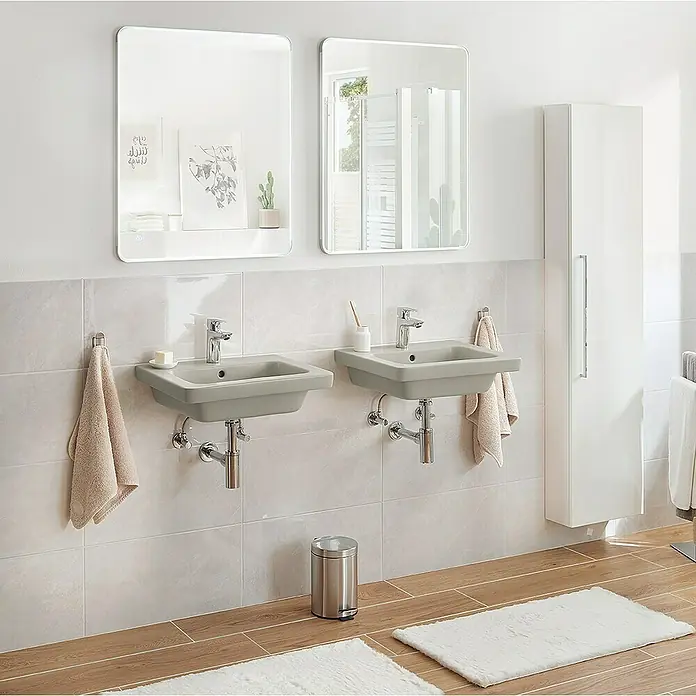 RAK Ceramics Feeling Waschtisch - 55 x 46 cm, Ohne Spezialglasur, Hahnloch: Mitte, Mit Überlauf, Grau, Matt - Ein modernes Badezimmer mit zwei grauen Waschbecken, jeweils mit Spiegeln und Handtüchern. Ein stilvoller, sauberer Raum.