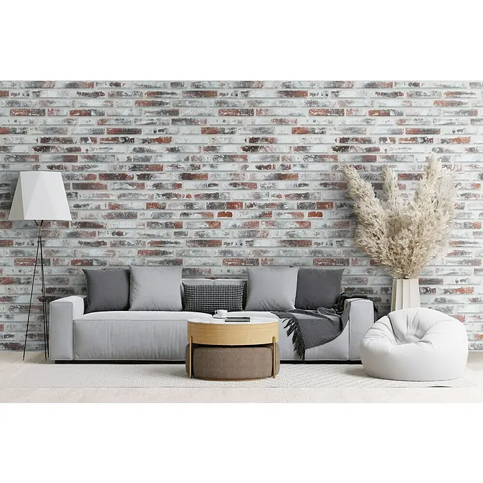 Celina Klinker Verblendstein Vintage Brooklyn - 5,2 x 24 cm, Rot/Weiß, Steinoptik - Elegantes Wohnzimmer mit stilvollem Sofa, Couchtisch und einer dekorativen Stehlampe vor einer Backsteinwand.