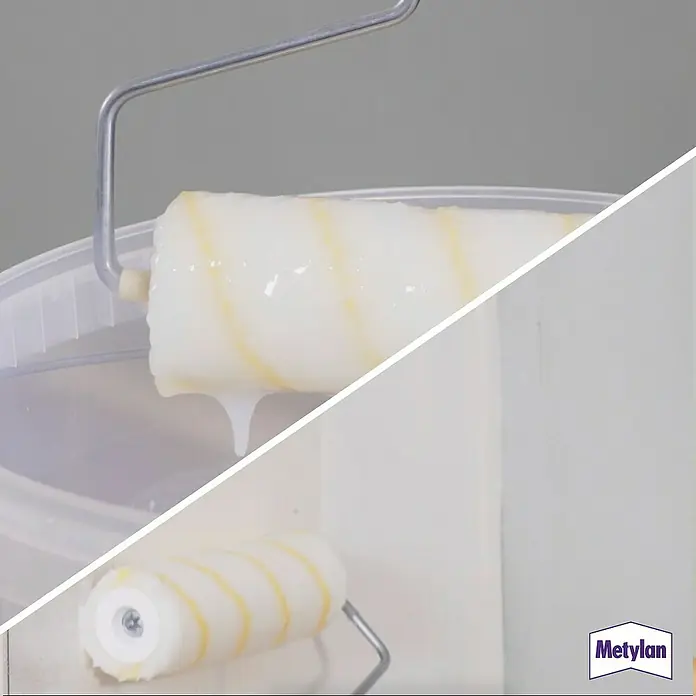 Metylan Tapetenkleister Renoviervlies & Glasfaser - 500 g - Ein Farbroller getränkt mit weißer Farbe, bereit für den Einsatz. Perfekt für Renovierungsarbeiten und zur Wandgestaltung.