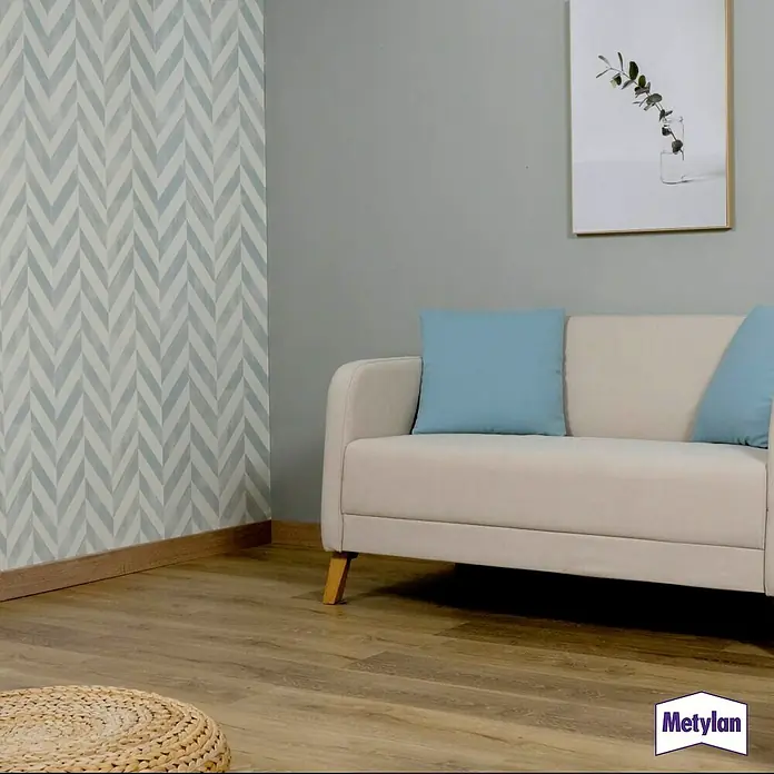 Metylan Tapetenkleister Flüssigkleisterkonzentrat Vlies - 500 g - Eine Nahaufnahme eines stilvollen, hellen Sofas mit blauen Kissen in einem modern eingerichteten Raum, mit Fokus auf das Möbeldesign.