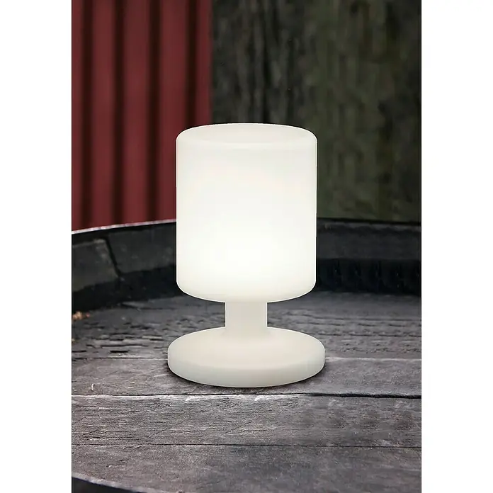Trio Lighting Lámpara decorativa solar Barbados - 1,5 W, L x An x Al: 17 x 17 x 25,5 cm, Blanco, IP44 - Primer plano de una lámpara de mesa blanca con pantalla redonda, situada sobre una superficie de madera oscura, que emite una luz cálida y difusa.