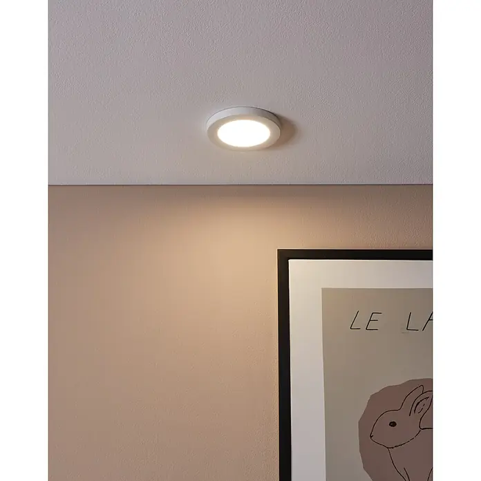 Eglo LED-Einbauleuchte rund FUEVA FLEX - 5,5 W, Ø x H: 11,7 x 0,2 cm, Weiß, Neutralweiß - Eine Nahaufnahme einer runden, weißen Deckenleuchte, die an einer Decke montiert ist und warmes Licht abgibt, mit einer Wand und einem Bild darunter.