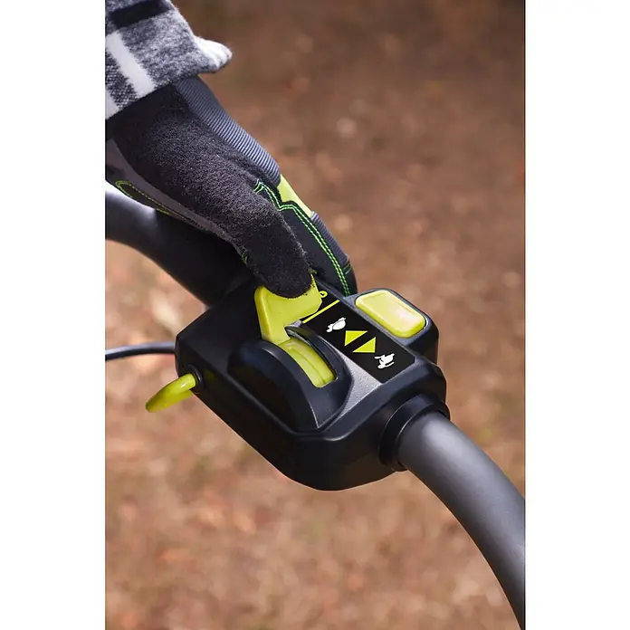 Ryobi Max Power Akku-Bodenhacke RY36CVXA-0 - Anzahl Akkus: Ohne Akku, Li-Ionen - Nahaufnahme der Steuerung eines Gartenwerkzeugs mit Hand, die einen grünen Schalter bedient.