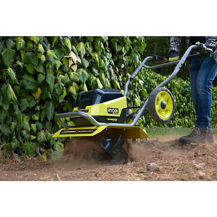 Ryobi Max Power Akku-Bodenhacke RY36CVXA-0 - Anzahl Akkus: Ohne Akku, Li-Ionen - Der Ryobi Kultivator in Aktion, der den Boden für die Gartenarbeit vorbereitet. Er ist gelb, kompakt und benutzerfreundlich für kleine Gärten.