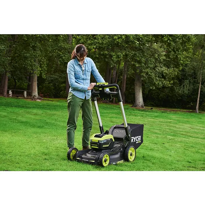 Ryobi Max Power Akku-Rasenmäher RY36LMXSP53A-160 - 36 V, 1 Akku, 6 Ah, Schnittbreite: 53 cm - Eine Frau bedient einen Ryobi-Rasenmäher im Freien. Das Gerät ist in Schwarz und Grün gehalten und verfügt über einen Grasfangkorb.