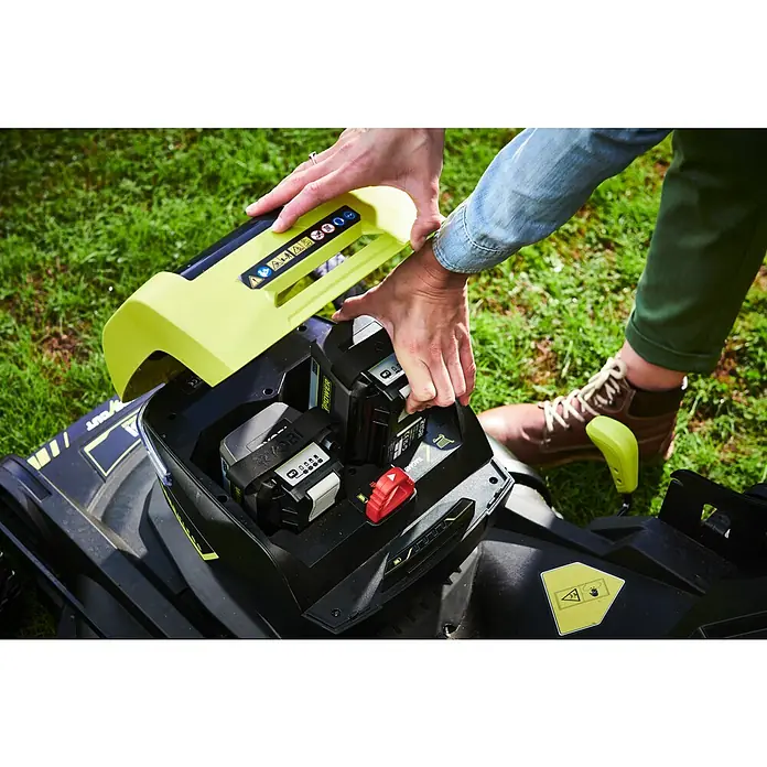 Ryobi Max Power Akku-Rasenmäher RY36LMXSP53A-160 - 36 V, 1 Akku, 6 Ah, Schnittbreite: 53 cm - Eine Person setzt einen Akku in einen Rasenmäher ein. Die Akkus sind von Ryobi und schwarz.