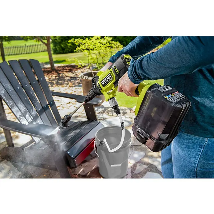 Ryobi Max Power Akku-Hochdruckreiniger RY36PWX41A-0 - 36 V, Ohne Akku, Max. Druck: 41 bar, Fördermenge: 160 l/h - Ein Mann reinigt mit einem gelben Ryobi Akku-Hochdruckreiniger einen schwarzen Gartenstuhl im Freien und benutzt dafür einen Eimer mit Wasser.