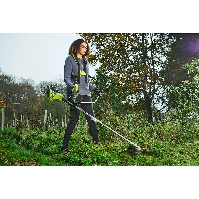 Ryobi Max Power Akku-Freischneider RY36BCX30A-9 - 36 V, Ohne Akku, Schnittbreite Faden: 40 cm, Schnittbreite Messer: 30 cm - Eine Frau bedient eine Ryobi Akku-Sense im Garten. Sie trägt eine Schutzbrille und einen Tragegurt für das Gerät.