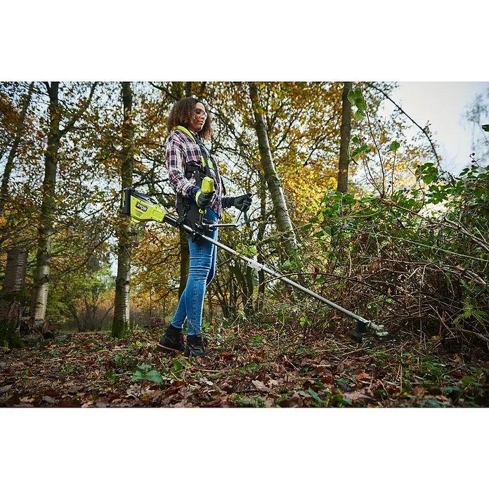 Ryobi Max Power Akku-Freischneider RY36BCX30A-9 - 36 V, Ohne Akku, Schnittbreite Faden: 40 cm, Schnittbreite Messer: 30 cm - Eine Frau benutzt einen Ryobi Freischneider mit Tragegurt, um in einem herbstlichen Wald Gestrüpp zu entfernen.