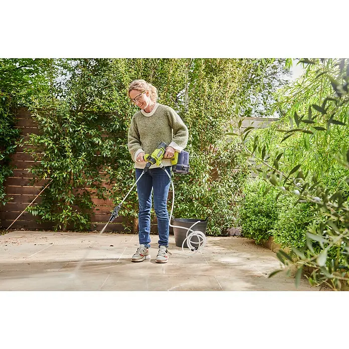 Ryobi Max Power Akku-Hochdruckreiniger RY36PWX41A-0 - 36 V, Ohne Akku, Max. Druck: 41 bar, Fördermenge: 160 l/h - Frau reinigt Terrasse mit gelbem Akku-Hochdruckreiniger von Ryobi. Praktisches Gerät für den flexiblen Einsatz im Garten und rund ums Haus.