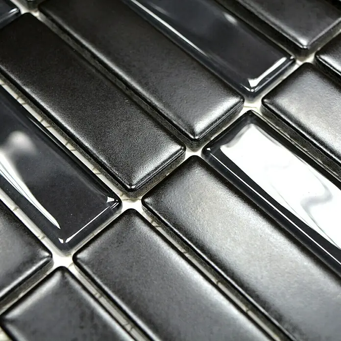 Mosaikfliese Stäbchen Mix ST 365 - 29,7 x 29 cm, Schwarz, Matt - Nahaufnahme von schwarzen, rechteckigen Glasmosaikfliesen, die in einem Fischgrätenmuster angeordnet sind und ein modernes Design zeigen.