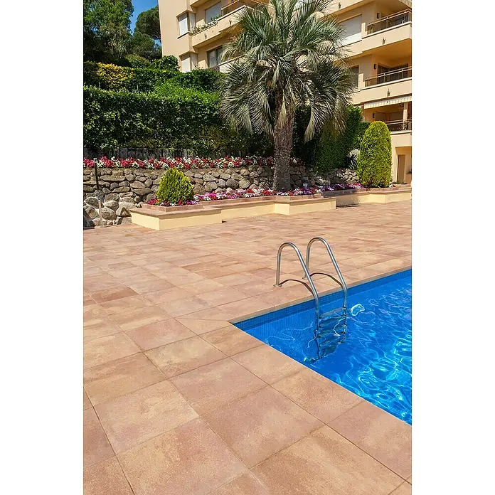 SAS Tessera Poolrandplatte - 32,8 x 50 x 6 cm, Bronze, Beton - Schwimmbad mit Edelstahlleiter, umgeben von beigefarbenen Fliesen, ideal für entspannende Sommertage.