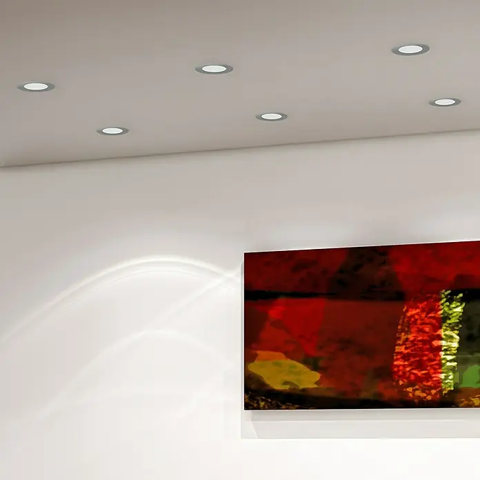 Alverlamp Downlight LED empotrable DLP - 18 W, Ø x Al: 22,1 x 2,5 cm, Blanco, Blanco neutro - Luces de techo brillantes iluminan una habitación moderna con una obra de arte en la pared.