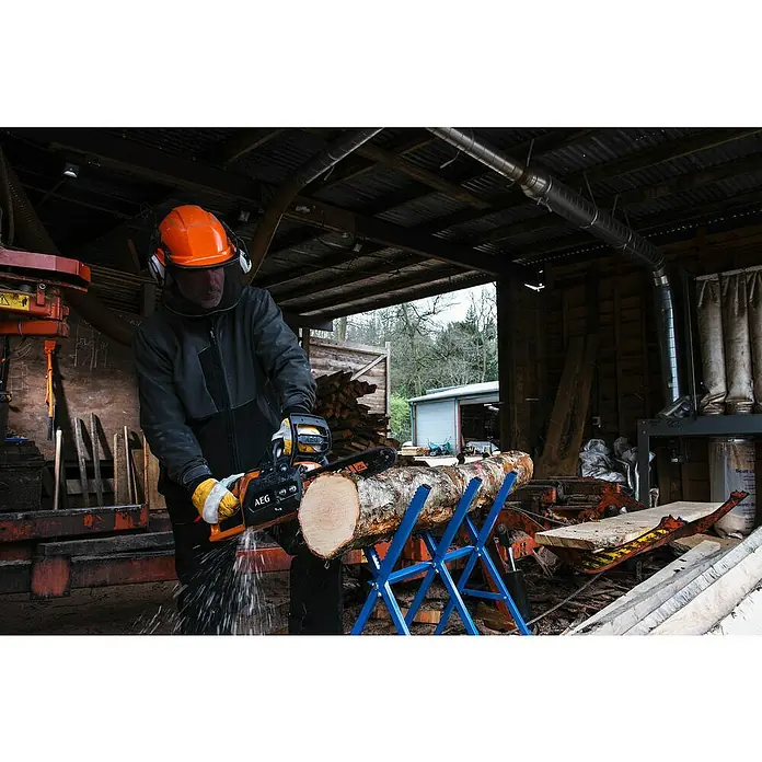 AEG Akku-Kettensäge ACS18B30 - 18 V, Li-Ionen, Ohne Akku, Schwertlänge: 30 cm - Ein Mann sägt mit einer AEG-Kettensäge ein Holzstück auf einem blauen Sägebock. Er trägt Schutzkleidung für seine Sicherheit.