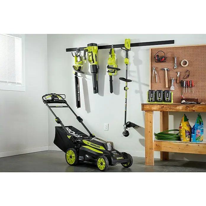 Ryobi Max Power Batterie-Ladegerät 3-fach RY36C3PA - Passend für: Ryobi 36V Akkus - Eine Auswahl an Ryobi-Gartengeräten, darunter ein Rasenmäher, eine Heckenschere, ein Laubbläser und eine Motorsense, sind übersichtlich an einer Wandhalterung angebracht.