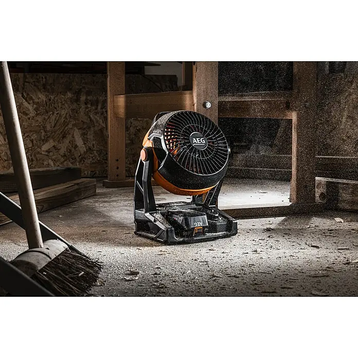 AEG Pro 18V Akku-Ventilator BAF 18 - 18 V, Ohne Akku, 900 m³/h - AEG Akku-Ventilator im Werkstatt-Ambiente. Der Ventilator ist schwarz und orange, und er steht auf einem staubigen Betonboden.