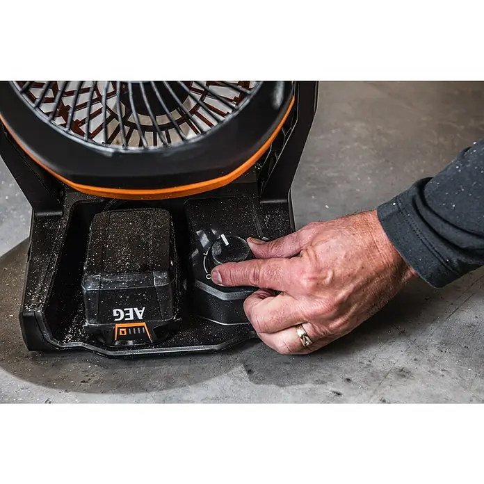 AEG Pro 18V Akku-Ventilator BAF 18 - 18 V, Ohne Akku, 900 m³/h - Nahaufnahme eines AEG-Akkus, der in einen Ventilator eingesetzt wird, mit einer Hand, die den Geschwindigkeitsregler einstellt.