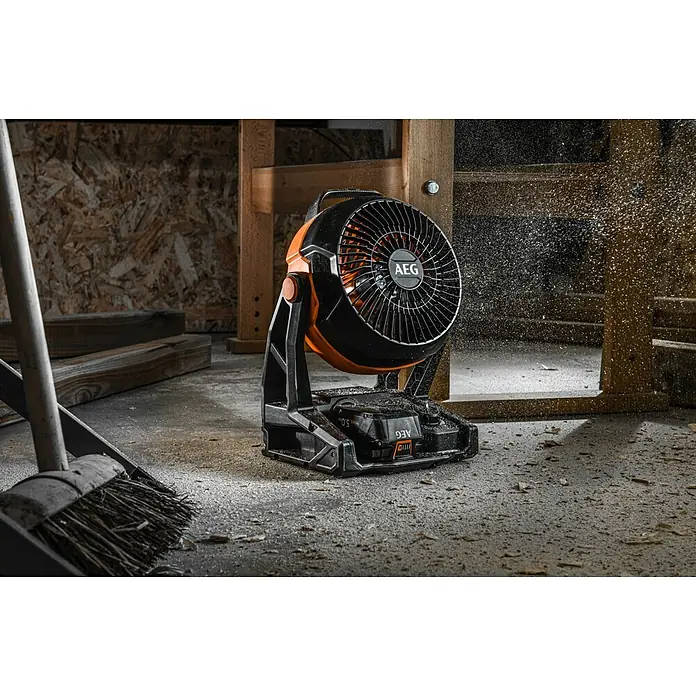 AEG Pro 18V Akku-Ventilator BAF 18 - 18 V, Ohne Akku, 900 m³/h - Nahaufnahme eines AEG-Akkubetriebenen Ventilators in einer Werkstatt mit herumfliegenden Sägespänen.