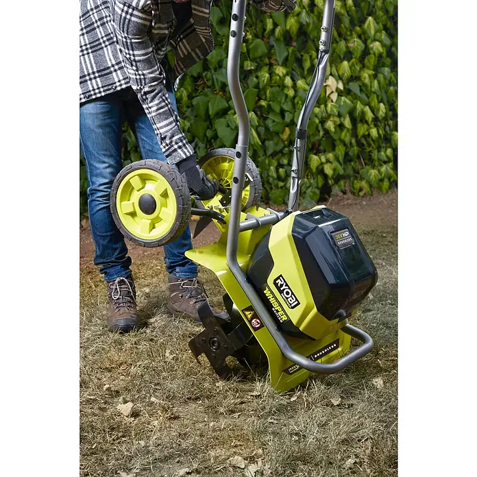 Ryobi Max Power Akku-Bodenhacke RY36CVXA-0 - Anzahl Akkus: Ohne Akku, Li-Ionen - Nahaufnahme eines Mannes, der einen Ryobi Akku-Bodenhacke im Garten bedient. Das Gerät ist gelb und schwarz und hat zwei gelbe Räder.