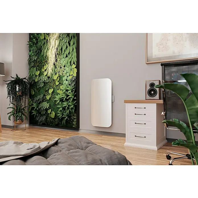 ClimaStar Speichersteinheizung WiFi Curve - Raumgröße bis ca. 18 m², Pearl White - Nahaufnahme eines weißen Heizkörpers an der Wand in einem stilvollen Raum mit Pflanzen.