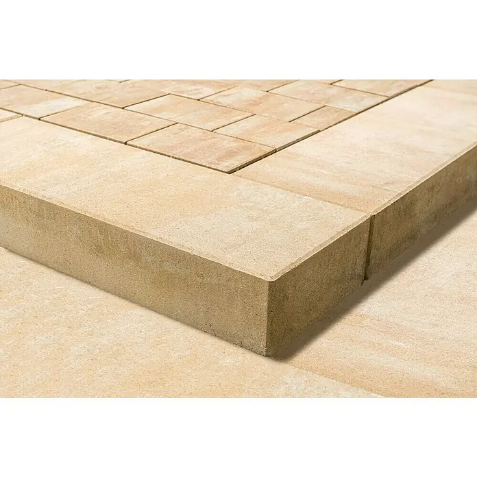 Diephaus Blockstufe Visalia - Sandstein, 100 x 35 x 15 cm, Beton - Nahaufnahme eines hellbraunen Pflastersteinrandes, der einen gepflasterten Bereich umgibt. Texturierte Oberfläche, ideal für Garten- und Landschaftsbauprojekte.