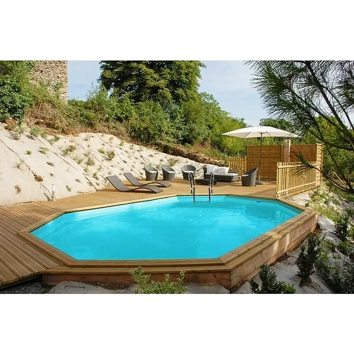Gre Piscina de madera Avocado - L x An x Al: 656 x 456 x 131 cm, Natural, 24.700 l - Piscina enterrada con cubierta de madera y escalera de piscina, rodeada de tumbonas y muebles de jardín bajo una sombrilla en una terraza jardín.
