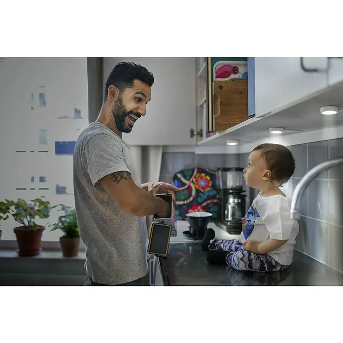 Ledvance LED-Unterbauleuchten-Set Spot Puck - Warmweiß, Weiß - Ein Vater zeigt seinem Kind eine wiederaufladbare tragbare Leuchte. Diese vielseitige Lampe ist ideal für jeden Raum und bietet praktisches Licht.