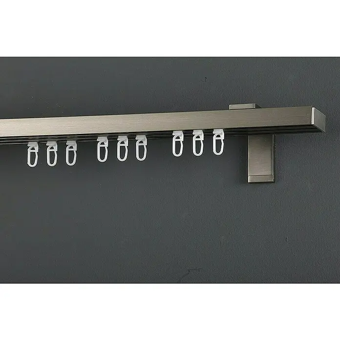 Expo Ambiente Gardinenprofil Smart Set - Anzahl Läufe: 3 Stk., Edelstahloptik, 210 cm - Nahaufnahme einer Vorhangschiene aus Metall mit weißen Aufhängern an einer grauen Wand.