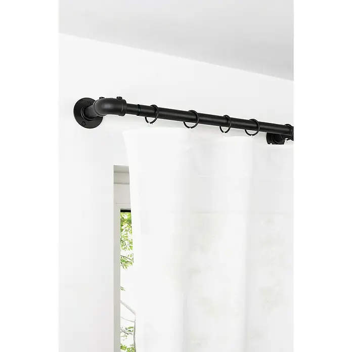 Stilgarnitur Industrial - Schwarz, Länge Gardinenstange: 160 cm - 280 cm - Blick auf eine schwarze Vorhangstange im Industrial-Stil mit weißen Vorhängen und Ringen, montiert an einer weißen Wand über einem Fenster.