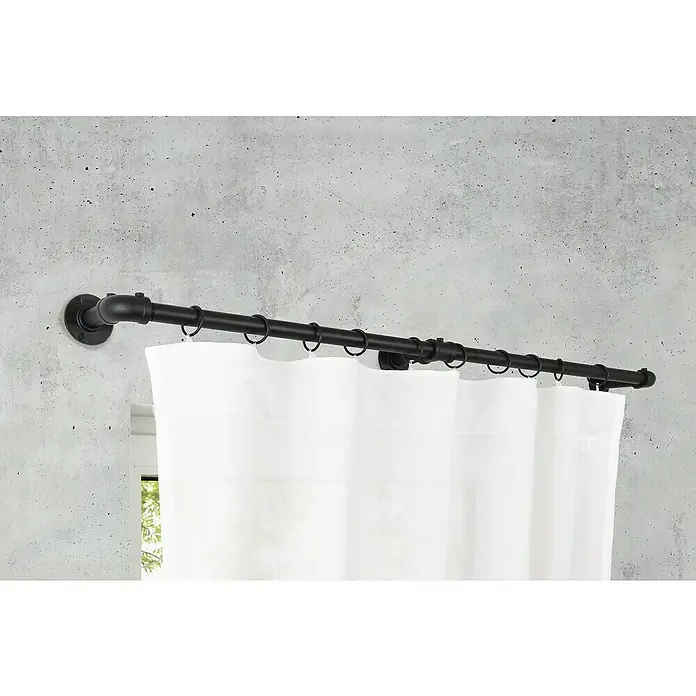 Stilgarnitur Industrial - Schwarz, Länge Gardinenstange: 160 cm - 280 cm - Eine schwarze Gardinenstange im industriellen Stil mit weißen Vorhängen vor einer Betonwand.