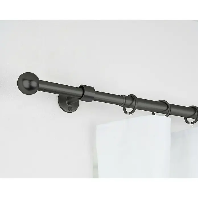 Komplettgarnitur 2in1 - Schwarz, 120 cm - 210 cm, Metall, Ausziehbar - Nahaufnahme einer schwarzen Gardinenstange mit Endknopf und Ringen an einer weißen Wand, die eine elegante Fensterdekoration zeigt.