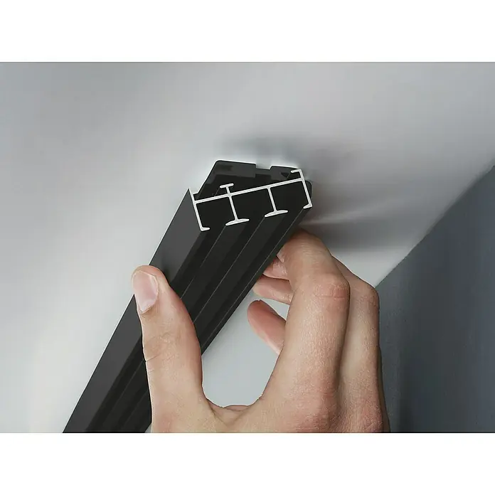 Expo Ambiente Gardinenprofil Smart-Set - Anzahl Läufe: 3 Stk., Schwarz, 160 cm - Ein schwarzes LED-Profil wird von einer Hand gehalten, mit Fokus auf das Design und die Funktionalität für moderne Beleuchtungslösungen.