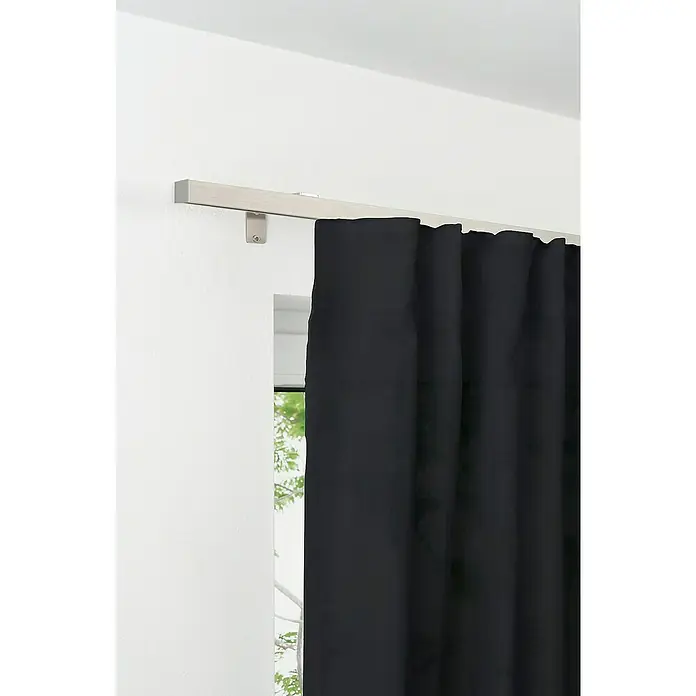 Komplettgarnitur All-in - Edelstahloptik, Länge Gardinenstange: 120 cm - 210 cm - Ein Detailbild einer blickdichten, schwarzen Gardine, die an einer hellen Metallschiene vor einem Fenster hängt und das Zimmer verdunkelt.