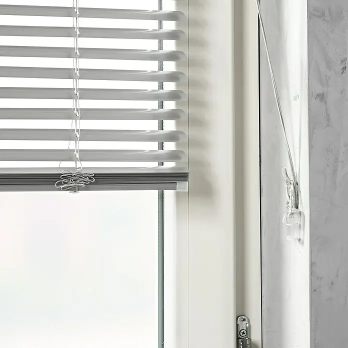 Zubehör-Set für Alu-Jalousien - 10 -tlg., Transparent - Nahaufnahme eines Fensters mit weißen Jalousien, die teilweise geschlossen sind und eine gedämpfte Lichtatmosphäre erzeugen.