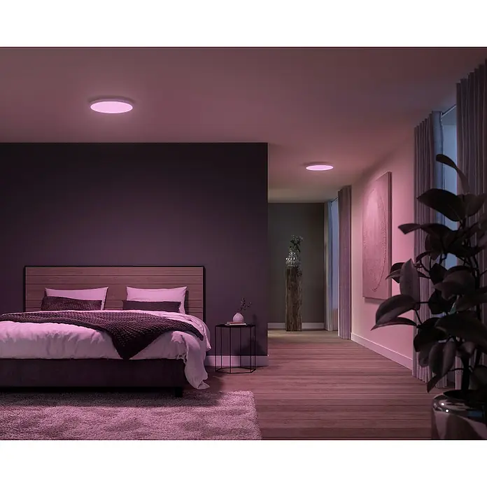 Philips Hue LED-Panel rund Surimu - 45 W, Ø x H: 395 x 4,7 cm, Weiß, Opal, RGBW - Elegantes Schlafzimmer mit smarter Deckenleuchte in Rosa, die eine beruhigende Atmosphäre schafft und das Ambiente des Raumes hervorhebt.
