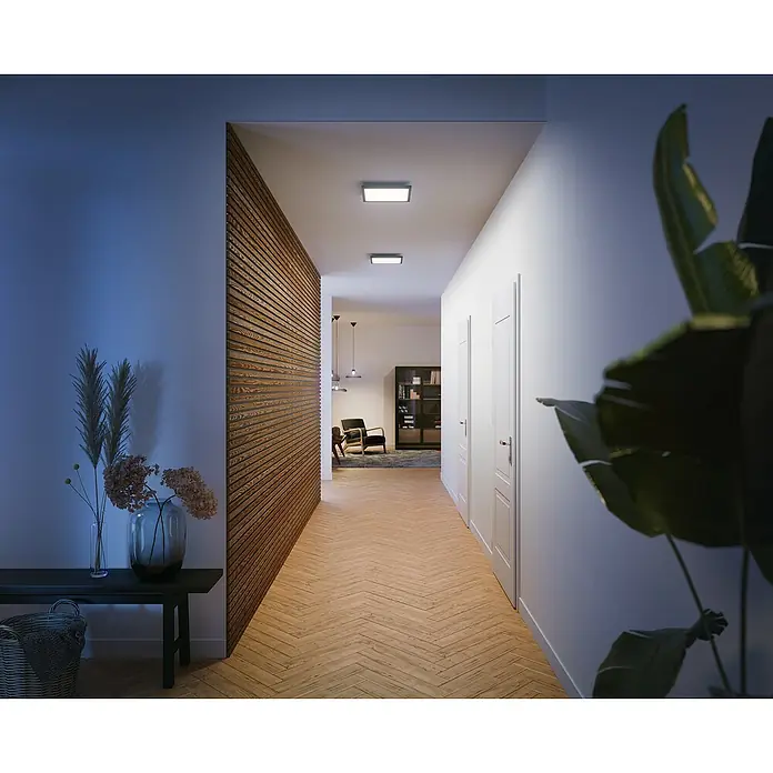 Philips Hue LED-Panel Aurelle - 19 W, L x B x H: 30 x 30 x 4,6 cm, Schwarz, Warmweiß - Ein langer Flur mit Philips Deckenleuchten, Holzvertäfelung und Holzboden. Die Beleuchtung ist modern und minimalistisch gestaltet.