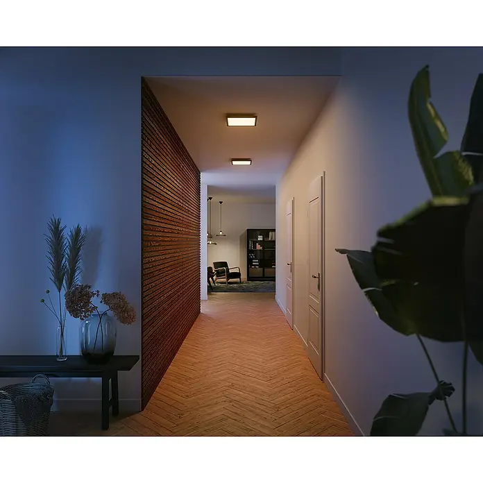 Philips Hue LED-Panel Aurelle - 19 W, L x B x H: 30 x 30 x 4,6 cm, Schwarz, Warmweiß - Ein langer Flur mit eingebauten Philips Deckenleuchten, die eine warme und einladende Atmosphäre schaffen. Blick in ein Wohnzimmer.