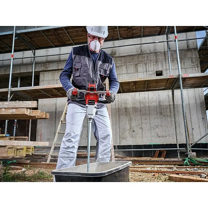 Einhell Professional Power X-Change 18V Farb- & Mörtelmischer TP-MX 18-2 Li BL Solo - 18 V, Ohne Akku, Durchmesser Rührer: 120 mm, M 14 - Ein Bauarbeiter mit Schutzmaske und Helm benutzt einen roten Einhell Mörtelrührer, um auf einer Baustelle Mörtel anzumischen.