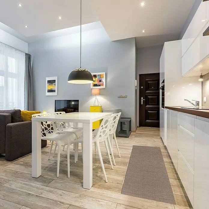 Teppichläufer Soft - Dunkelbeige, 150 x 50 cm, 79 % Polyvinylchlorid, 21 % Polyester - Helle Wohnung mit minimalistischem Essbereich. Der weiße Tisch und die Stühle stehen im Kontrast zum grauen Teppich. Moderne Lampe hängt über dem Tisch.