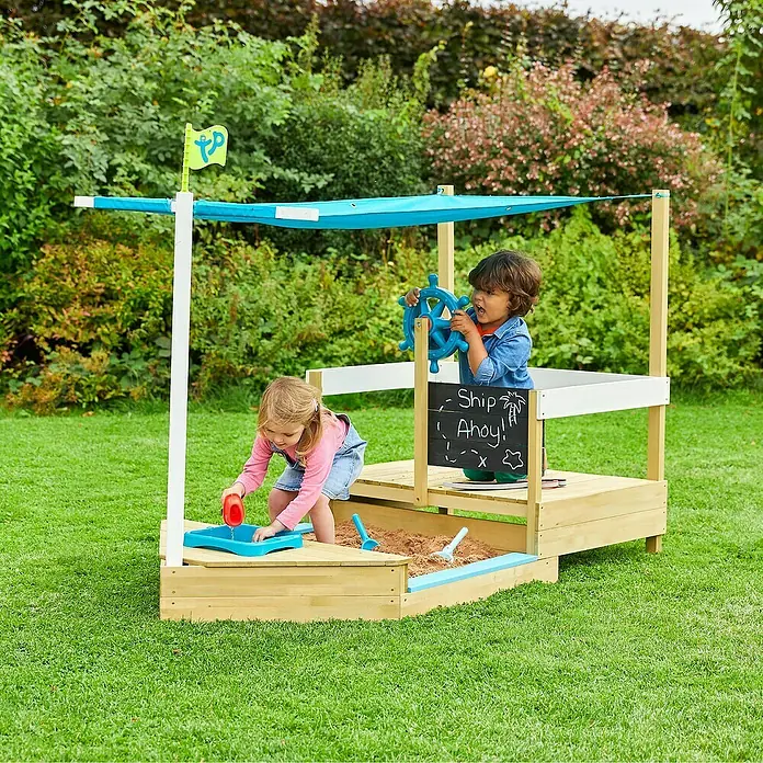 TP Toys Sandkasten Ahoy - 180 x 92 x 118 cm, Holz, Natur/Weiß, Blau - Ein TP Piraten-Sandkasten mit Markise, der mit zwei Kindern auf einem Rasenplatz spielt, bietet stundenlangen fantasievollen Spaß im Freien.