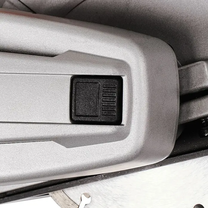 Einhell Mauernutfräse TE-MA 1700 - 1.700 W, Durchmesser Scheibe: 150 mm - Nahaufnahme eines schwarzen Entriegelungsknopfs an einer grauen Gehrungssäge, der eine einfache Bedienung und präzise Schnitte ermöglicht.