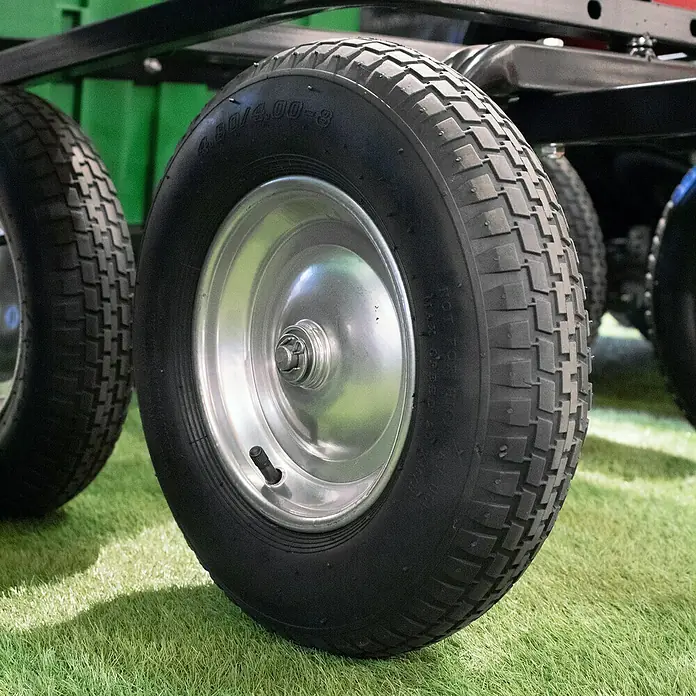 Güde Transportwagen Garten GGW 500 - 141 x 81 x 74 cm, 225 l - Nahaufnahme eines robusten, schwarzen Rades mit silberner Felge, ideal für Gartenwagen oder ähnliche Geräte, auf grünem Untergrund.