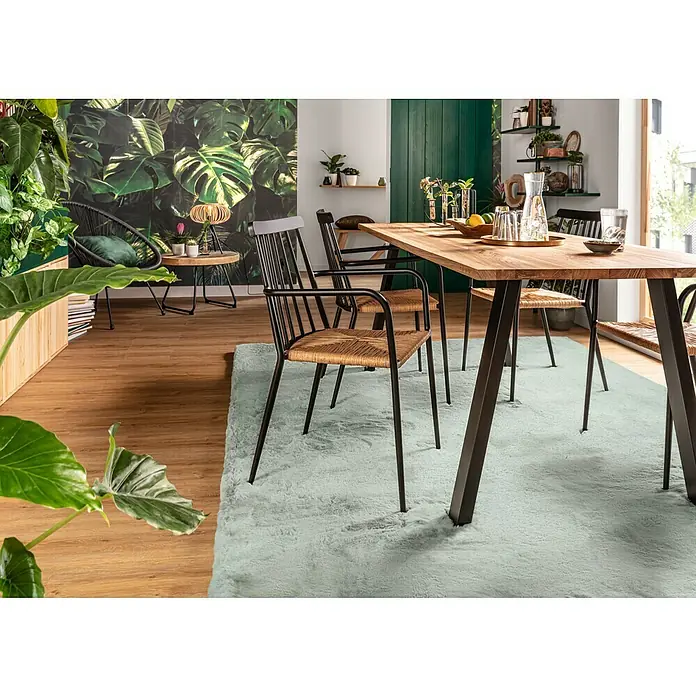 Fellteppich Happy - Jade, 290 x 200 cm, 100 % Polyester (Flor) - Ein einladender Essbereich mit einem Holztisch und Stühlen mit Rattan-Sitzfläche auf einem hellblauen Teppich.