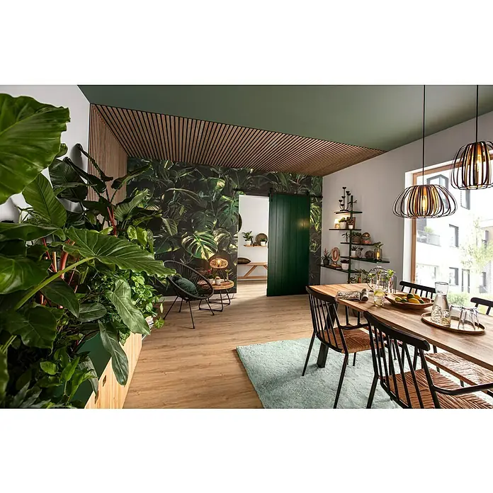 b!design Vinylboden Rigid Maxi Ashton Eiche1.220 x 228 x 4,8 mm, Landhausdiele, Ashton Eiche - Ein einladender Essbereich mit einem Holztisch, stilvollen Stühlen und hängenden Lampen, umgeben von üppigem Grün und einer grünen Akzentwand.