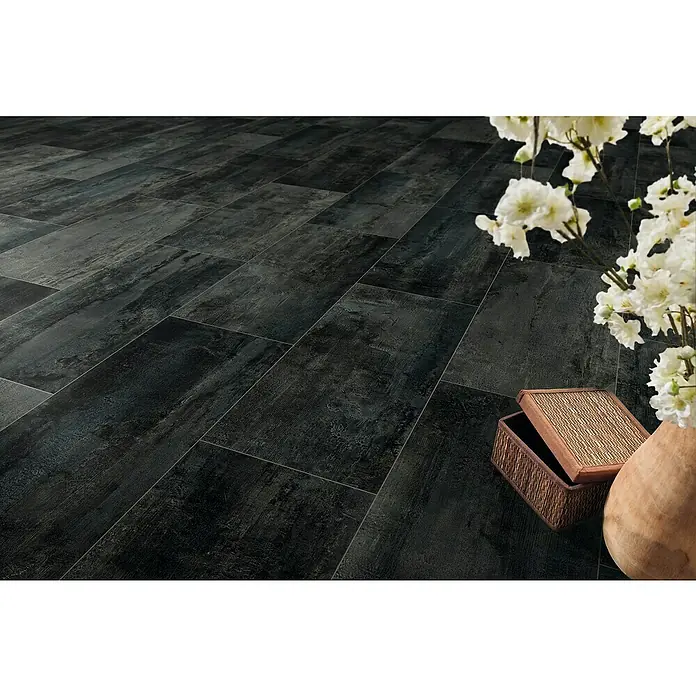 LOGOCLIC Designbodenmuster Element Flex Dark Tile - 297 x 322 x 7 mm, Fliesenoptik - Edler dunkler Bodenbelag mit Holzoptik, verlegt in einem stilvollen Raum mit Blumenarrangement und dekorativer Box.