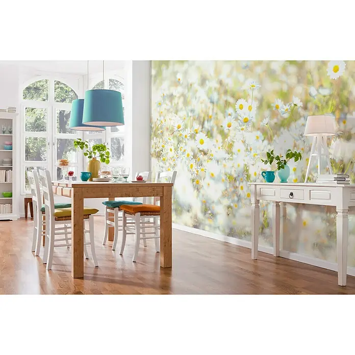 Komar Imagine Edition 3 - Stories Fototapete Daisies - 8 -tlg., B x H: 368 x 254 cm, Papier - Das Esszimmer verfügt über einen Holztisch mit weißen Stühlen und einen weißen Konsolentisch, wodurch ein helles und einladendes Ambiente entsteht.